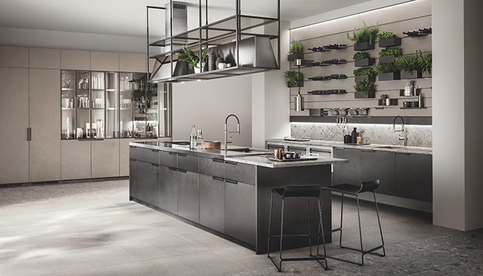 Scavolini’s Mia by Carlo Cracco kitchen features a wall panel with accessories such as open shelves, containers for herbs and spices, bowls and bottle racks, and a hanging structure above the island