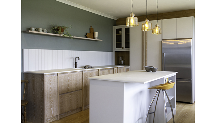 This Glaven kitchen from Naked Kitchens features a brushed limed-grain oak finish with white cabinetry and Caesarstone concrete worktops, complete with open shelving and ample storage space, wooden flooring, rattan accessories and plants to create the ultimate Scandi-inspired kitchen