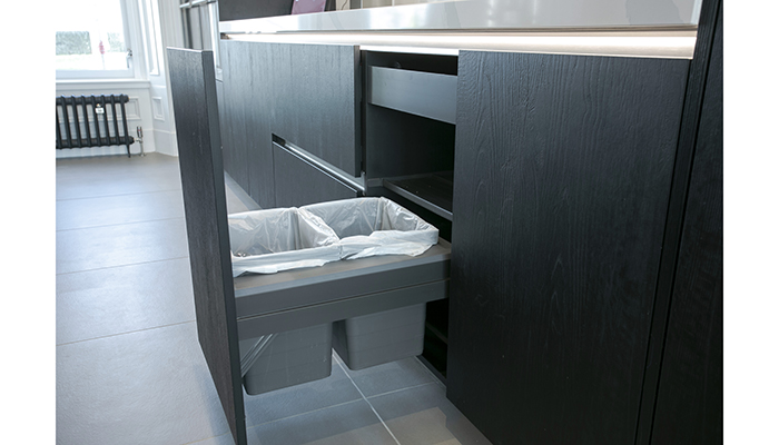Rotpunkt’s Zerox furniture, shown here in Sherwood Black, includes an integrated waste and recycling bin system as part of an island unit positioned in the wet zone of the kitchen, demonstrating that a waste management solution can look stylish in any high-end kitchen design