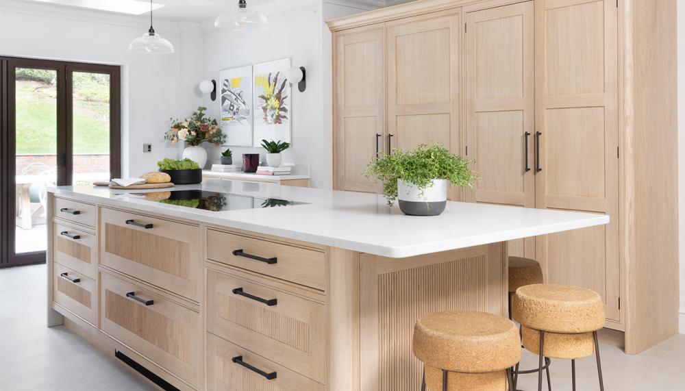 This wood-drenched in frame Scandi Bespoke kitchen by Searle & Taylor features a 3.2 x 1.4metre island with plain and reeded blond oak fronts and end panels, complete with seating area, and Novy vented downdraft induction hob. Photograph: Paul Craig